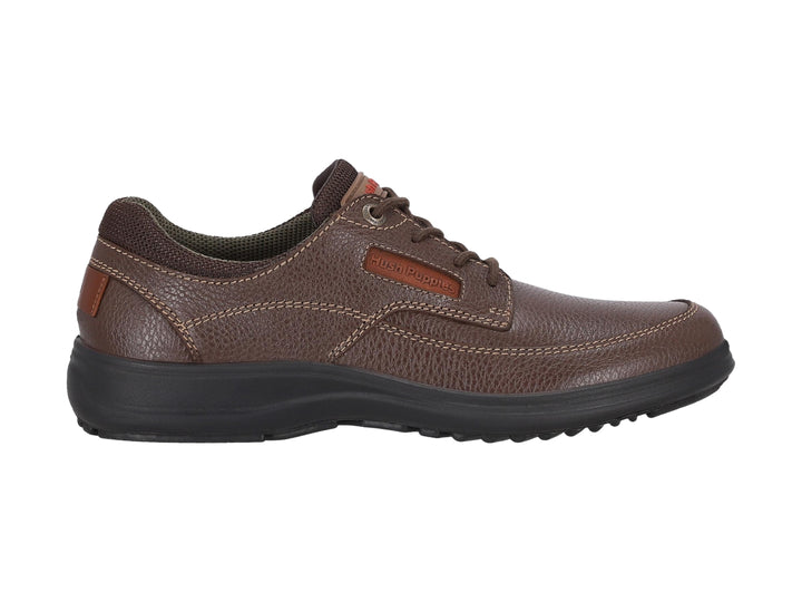 Zapato casual Hush Puppies de cuero marrón con suela negra y cordones.
