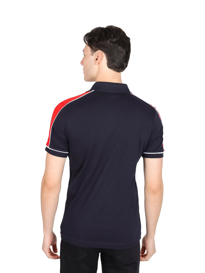 Hombre vistiendo playera polo azul marino con detalles en rojo y blanco y cierre frontal.
