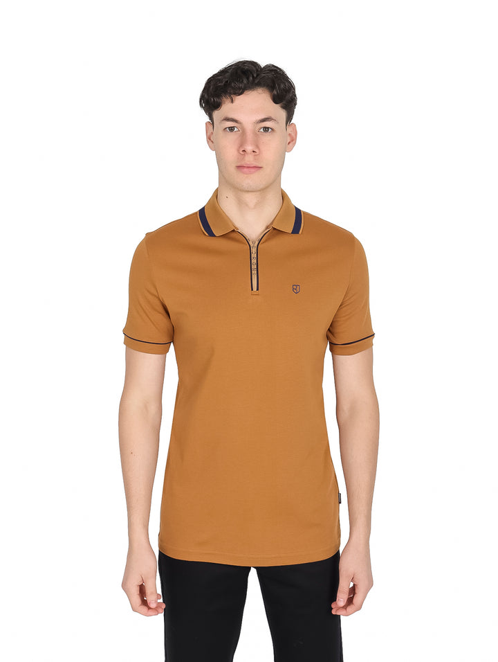 Hombre vistiendo playera polo color dorado con detalles en azul marino y cierre frontal.