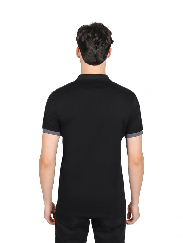 Hombre vistiendo playera polo color negro con detalles en gris oxford en cuello y mangas.