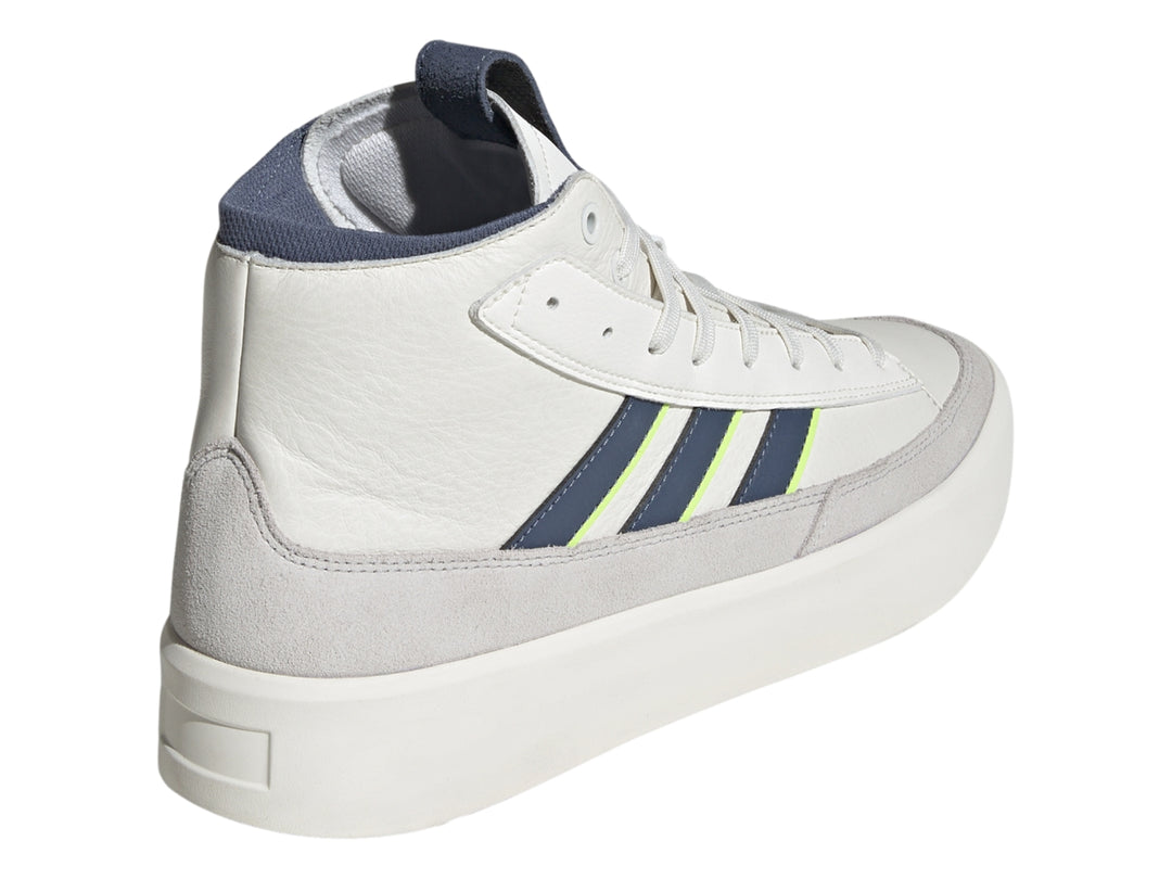 Tenis Adidas blancos de corte alto con franjas azul marino y verde lima y base gris.
