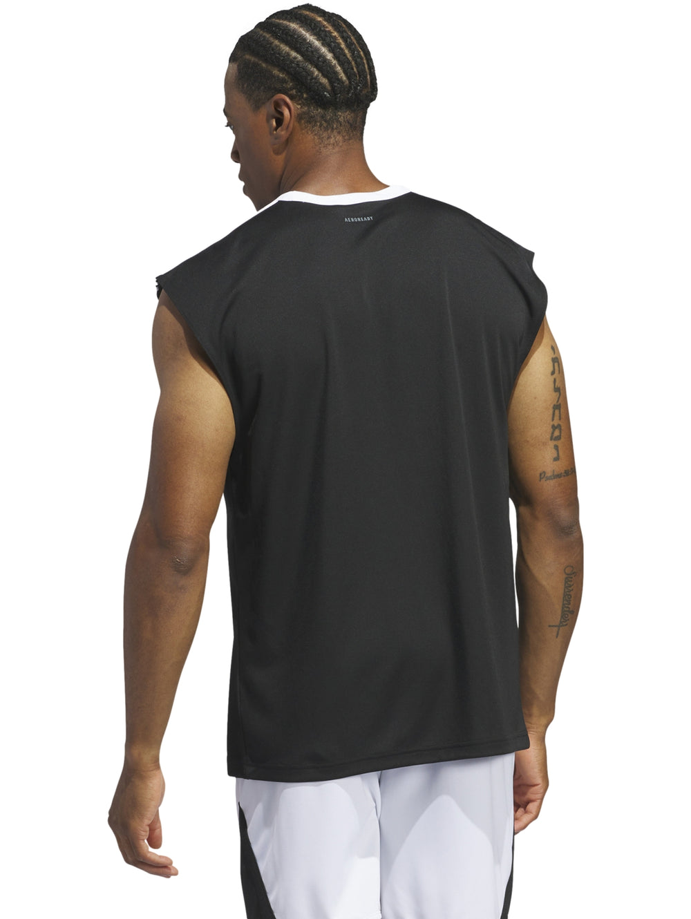 Hombre vistiendo camiseta deportiva sin mangas color negro con detalles blancos de la marca Adidas.