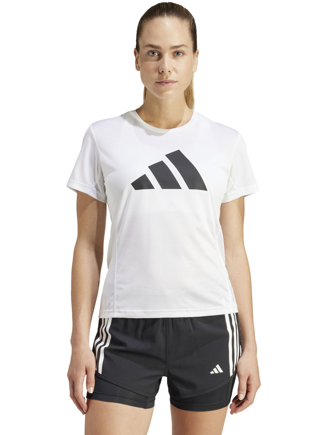 Camiseta deportiva blanca de manga corta con logo de Adidas en el pecho, modelada por una mujer.