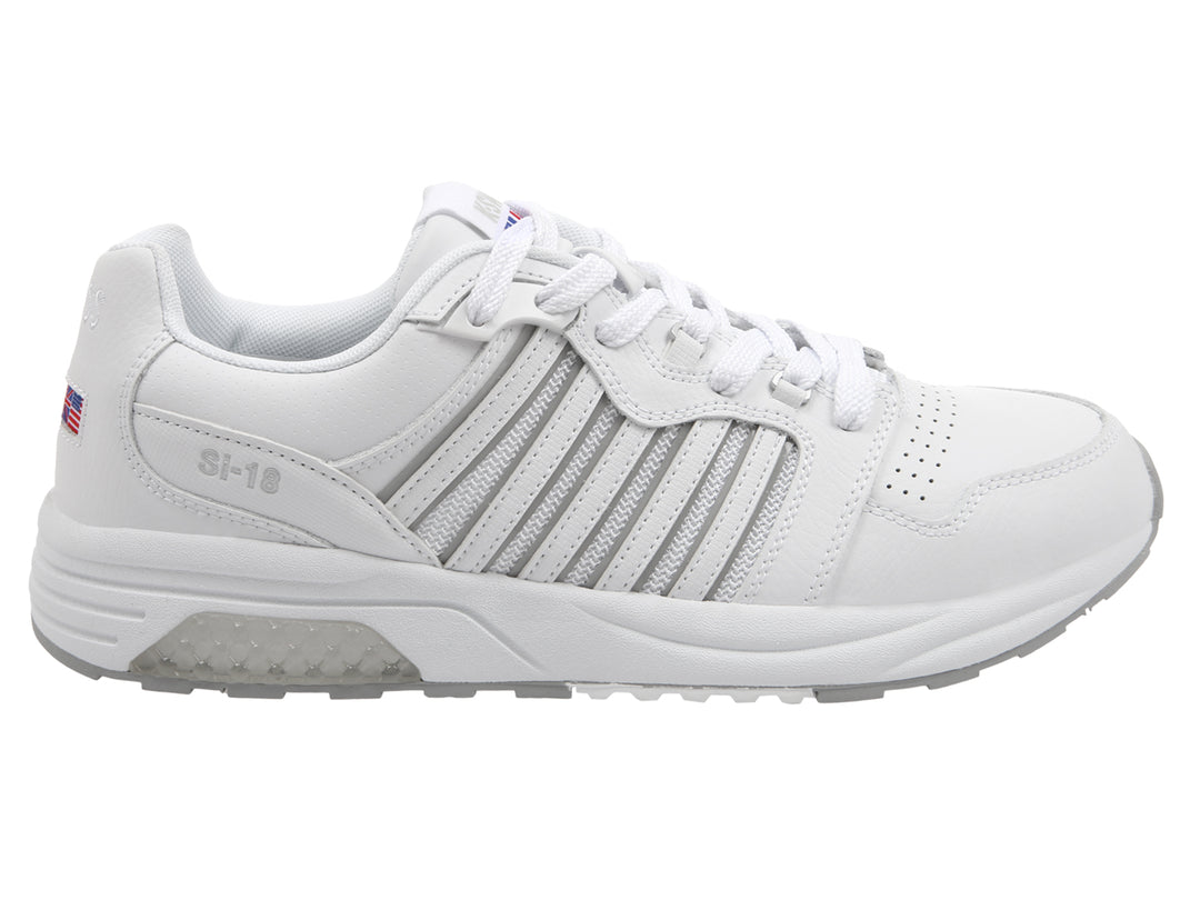 Tenis deportivos K-Swiss en color blanco con suela gris y detalles lineales laterales.