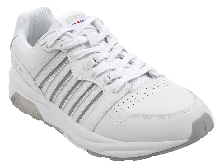Tenis deportivos K-Swiss en color blanco con suela gris y detalles lineales laterales.