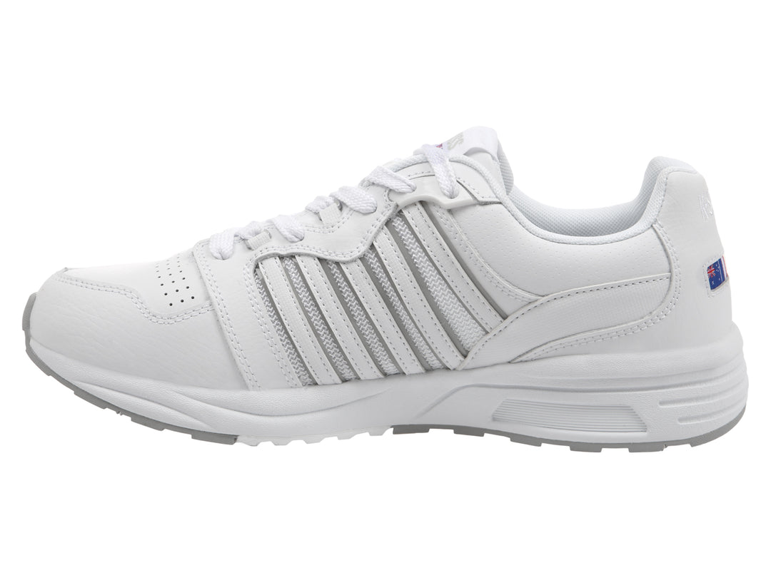 Tenis deportivos K-Swiss en color blanco con suela gris y detalles lineales laterales.