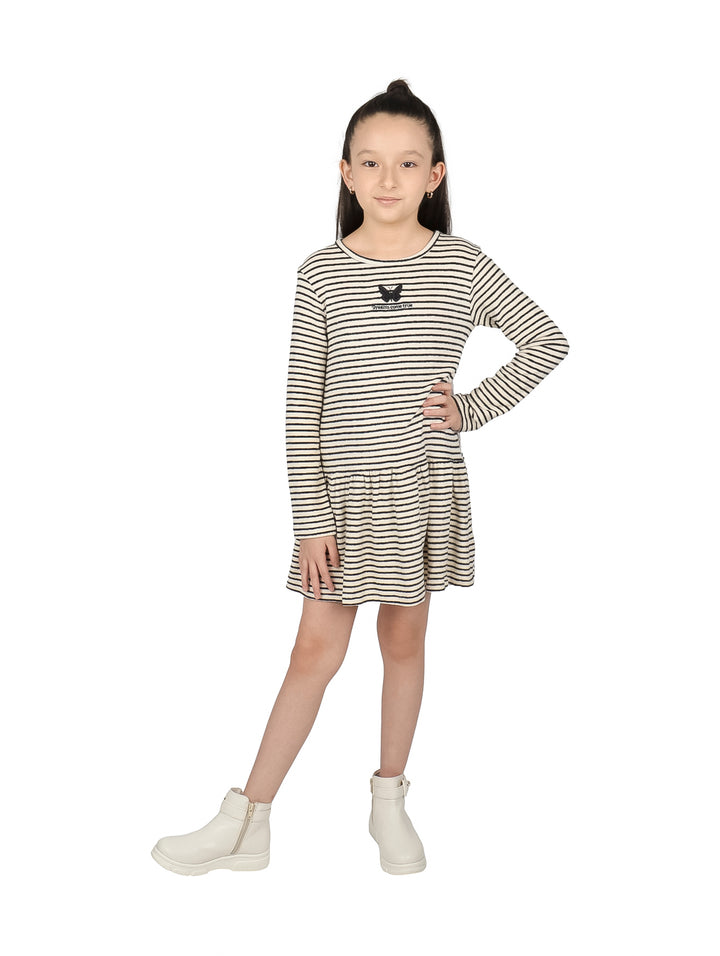 Niña con vestido corto a rayas color crudo y negro y botas blancas.