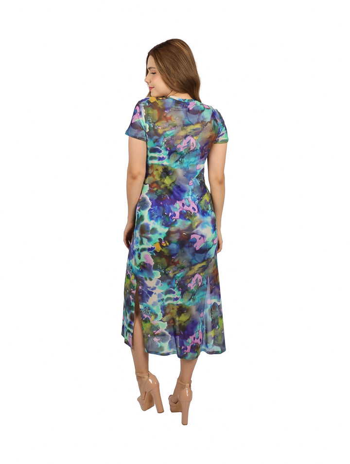 Mujer con vestido midi de manga corta y estampado multicolor estilo acuarela en tonos azules y púrpuras.