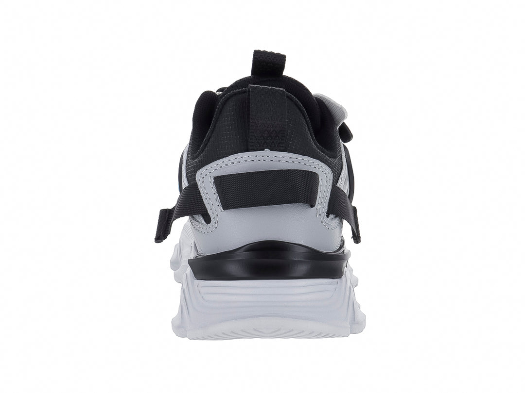 Tenis deportivos infantiles color gris y negro con suela blanca gruesa y detalles en azul claro.