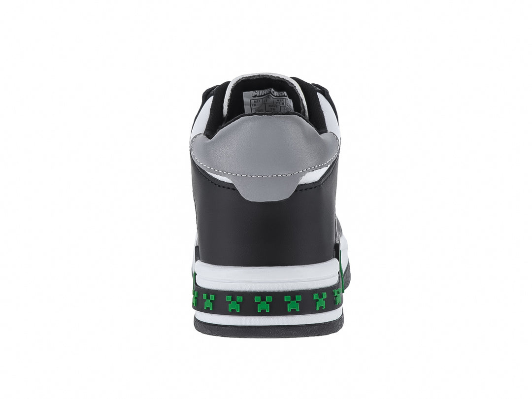 Tenis infantiles color negro y blanco con detalles verdes pixelados y texto Survival Mode.