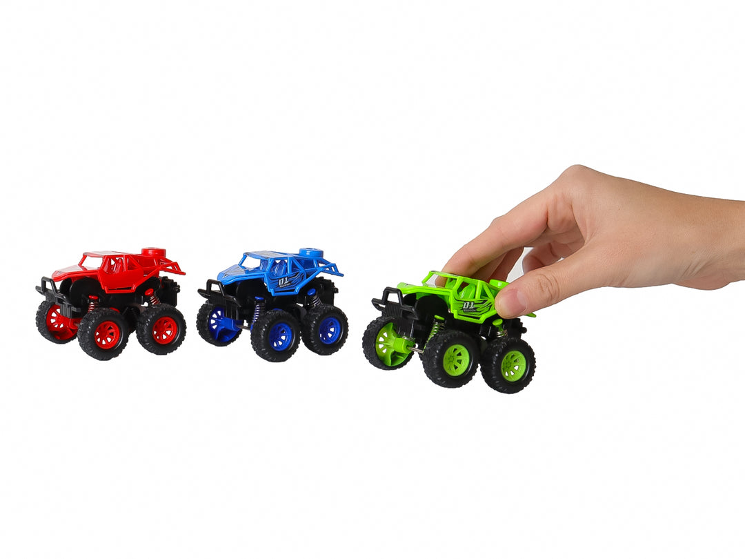 Set de tres vehículos de juguete tipo monster truck en colores verde, azul y rojo dentro de su empaque original.