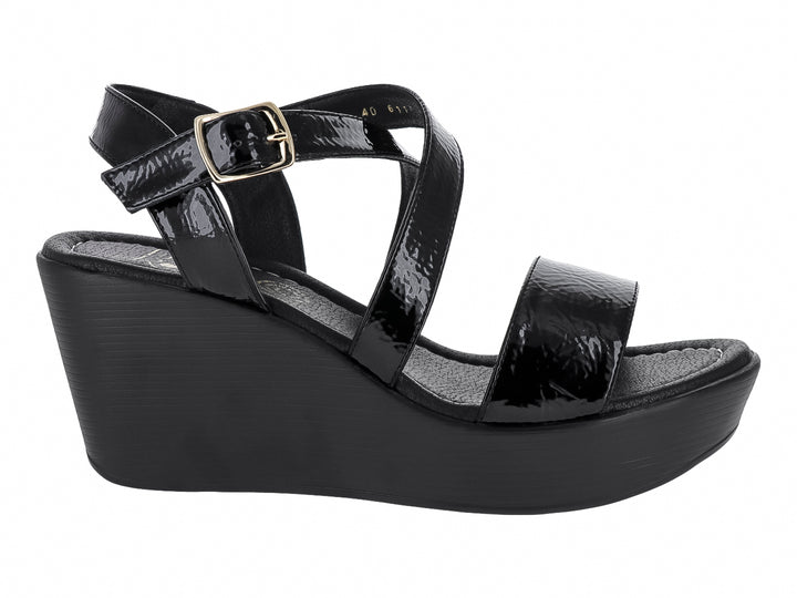 Sandalia de cuña color negro con tiras de charol brillante y hebilla dorada.