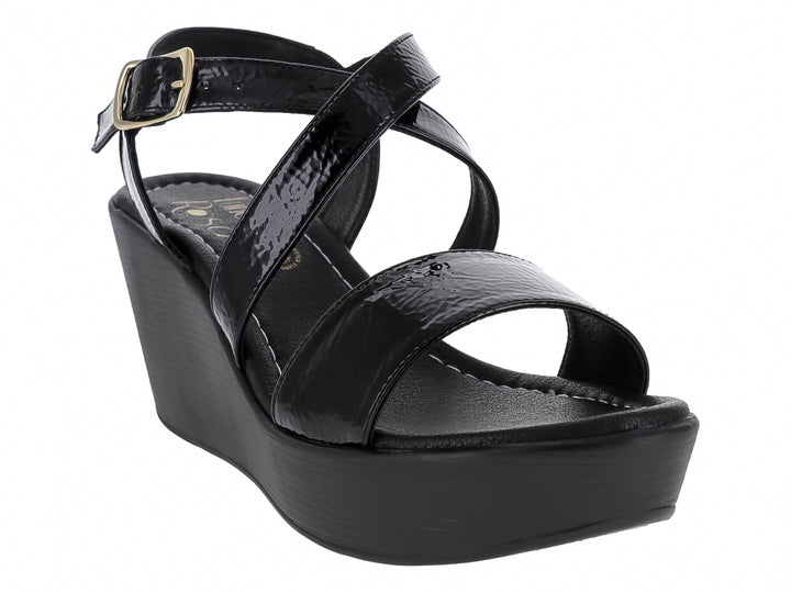 Sandalia de cuña color negro con tiras de charol brillante y hebilla dorada.