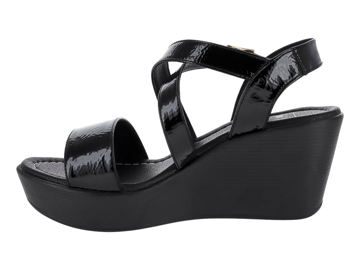 Sandalia de cuña color negro con tiras de charol brillante y hebilla dorada.