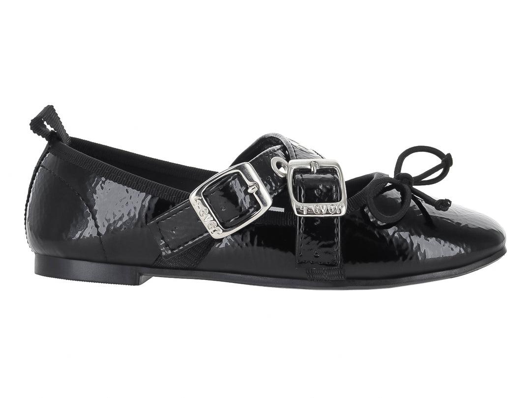 Zapato plano de charol negro con dos hebillas plateadas y un pequeño moño decorativo en la punta.