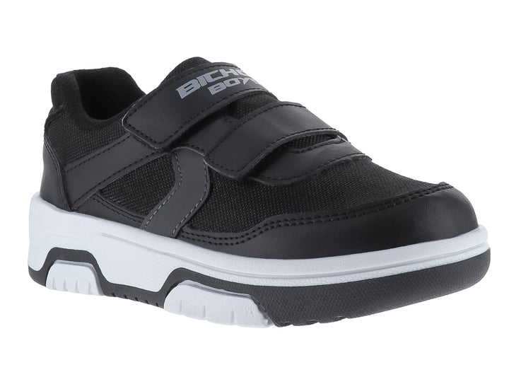 Zapato infantil color negro con suela blanca y cierre de velcro.