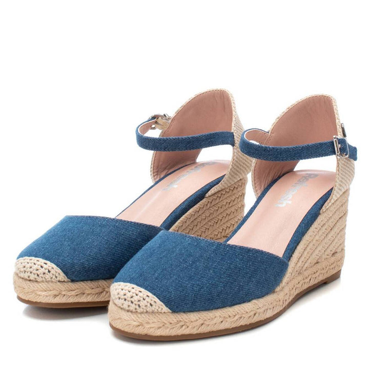 Sandalia XTI color azul navy con plataforma de cuña en esparto beige y correa ajustable al tobillo.