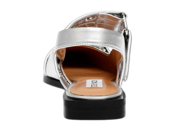 Zapato plano plateado con punta cuadrada y hebillas metálicas sobre suela negra.