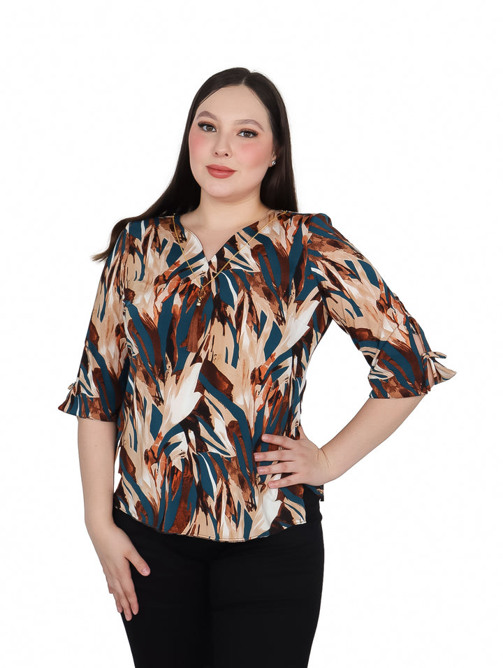 Mujer vistiendo blusa de licra estampada en tonos café, azul y blanco con collar integrado.