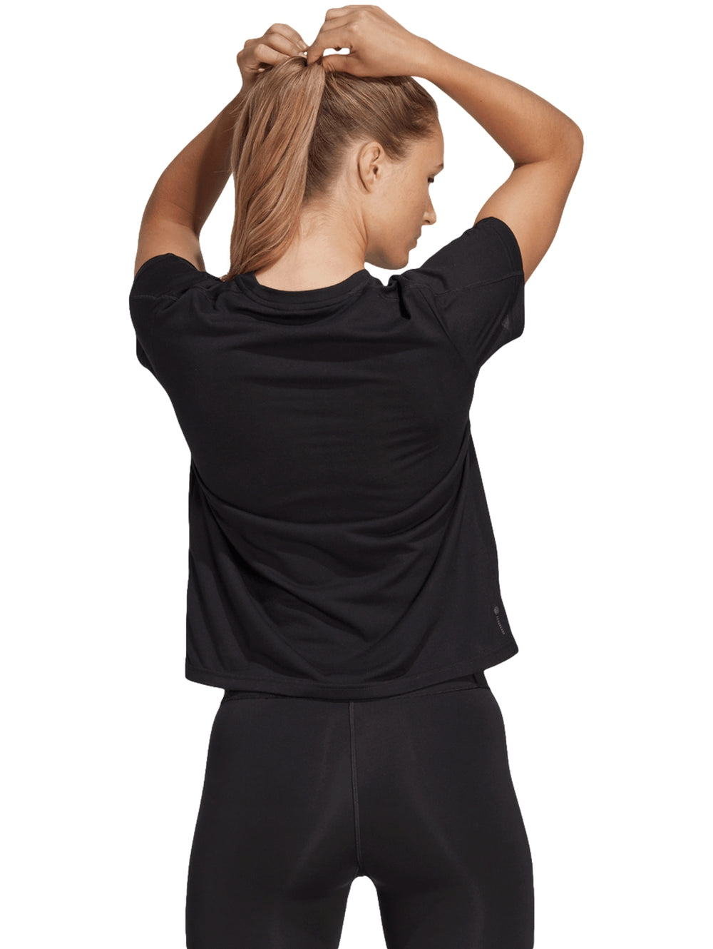Mujer vistiendo playera deportiva Adidas color negro de manga corta y cuello redondo con logo blanco al centro.
