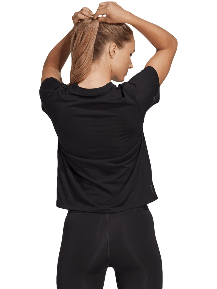 Mujer vistiendo playera deportiva Adidas color negro de manga corta y cuello redondo con logo blanco al centro.