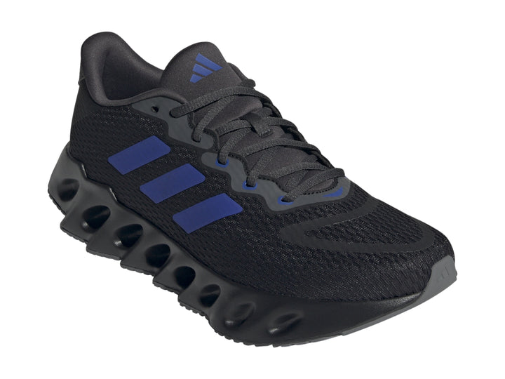 Tenis Adidas Switch Run color negro con tres franjas azules y suela ondulada para hombre.