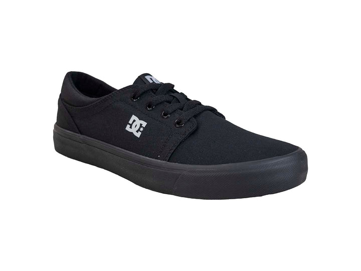 Tenis negros DC Shoes de tela con suela plana y logotipo blanco lateral.