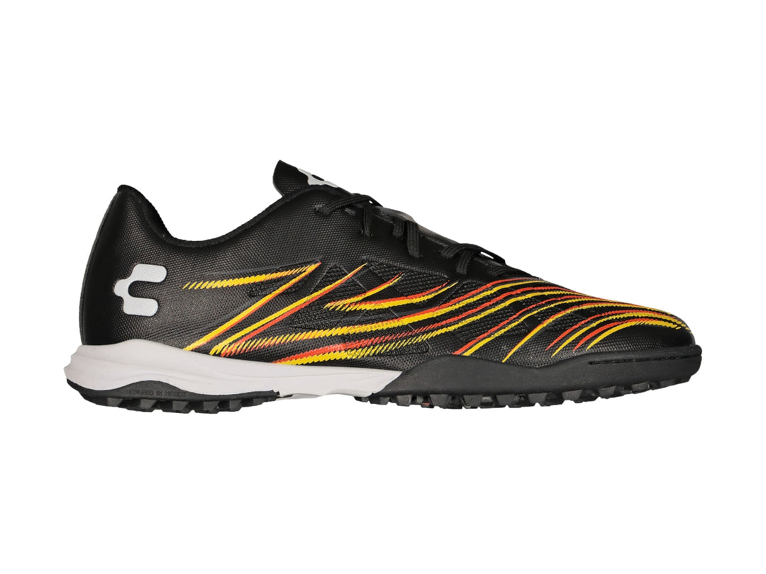Zapato de fútbol Charly color negro con rayas amarillas y naranjas, suela blanca y negra para pasto sintético.