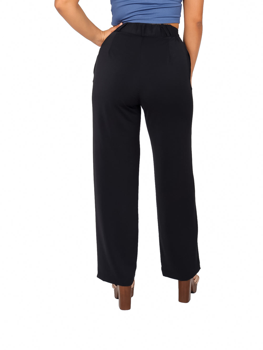Mujer vistiendo un pantalón básico liso de color negro con corte de pierna ancha y talle alto.