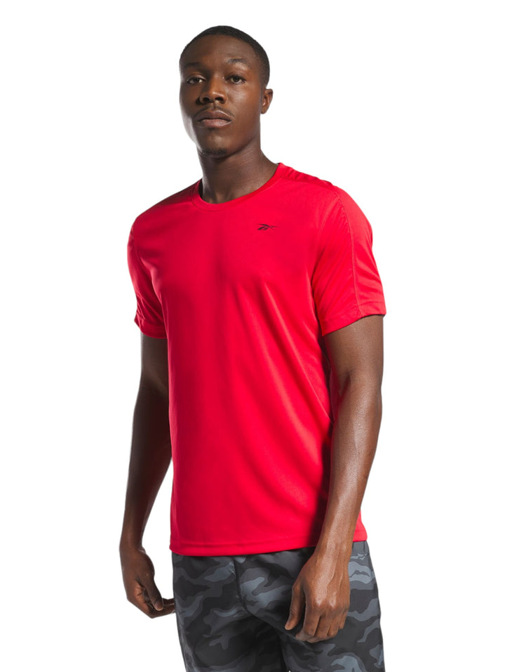 Hombre vistiendo una playera deportiva de manga corta color rojo marca Reebok.