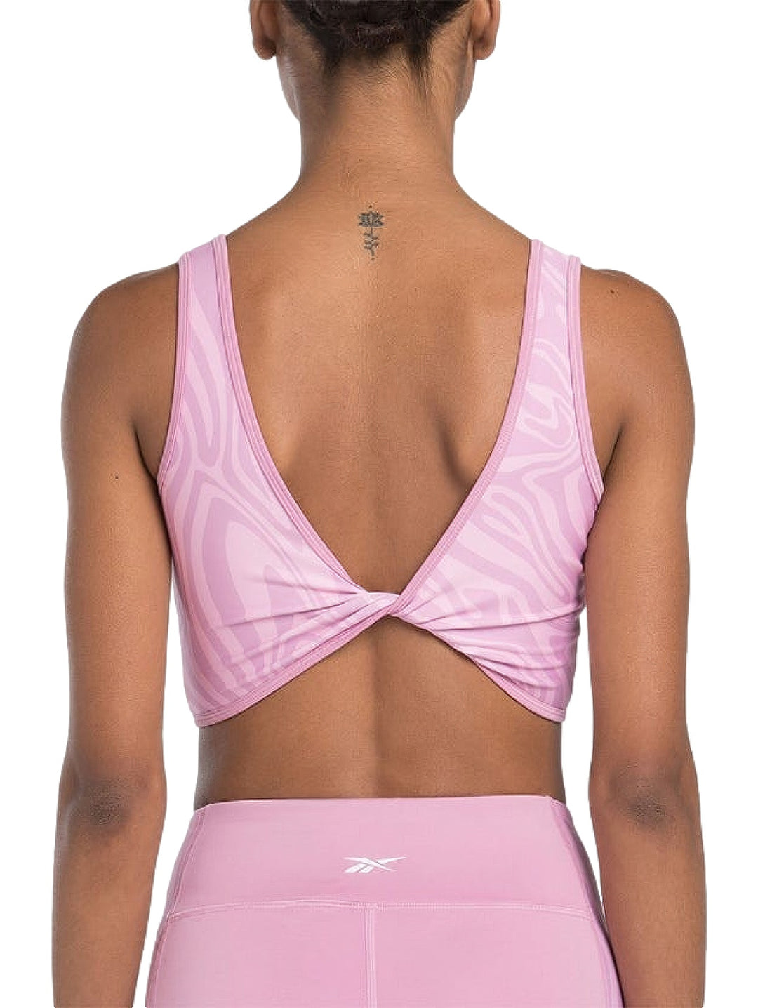 Bralette deportivo Reebok en color rosa con estampado abstracto ondulado y cuello redondo.