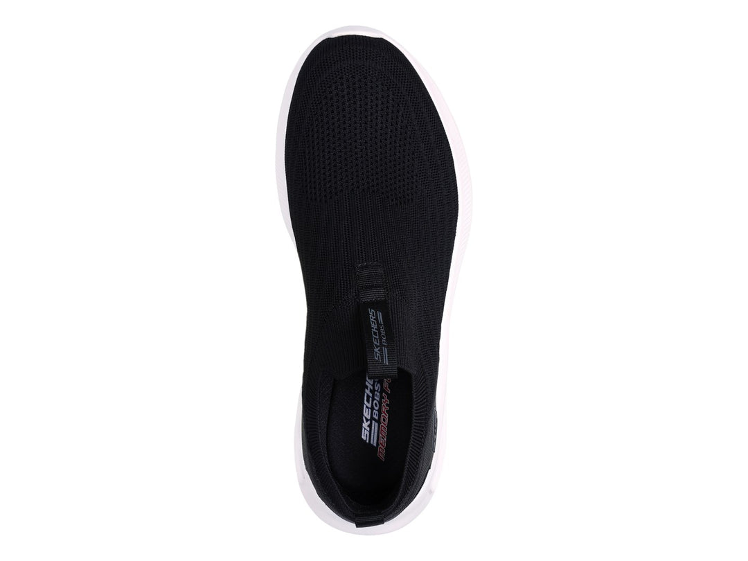 Tenis Skechers negros de tela sin cordones con suela blanca gruesa.
