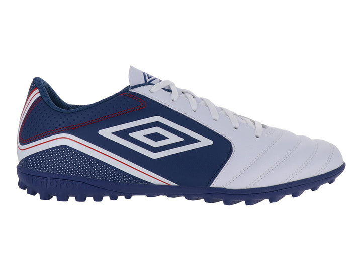 Zapato de fútbol Umbro color blanco y azul con detalles rojos y suela para césped sintético.
