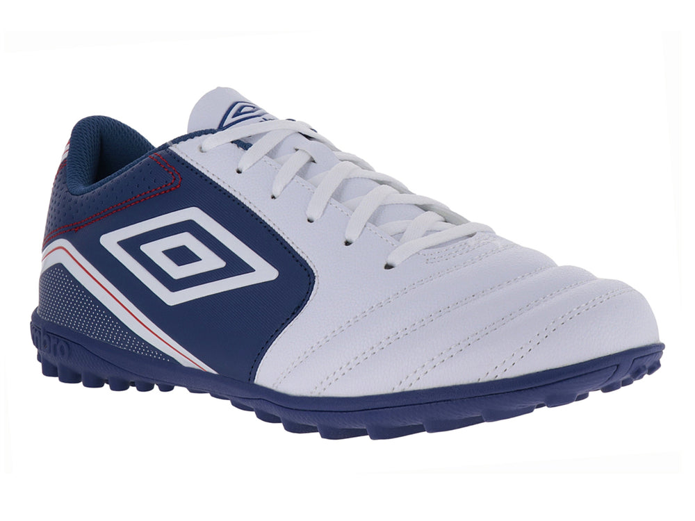 Zapato de fútbol Umbro color blanco y azul con detalles rojos y suela para césped sintético.