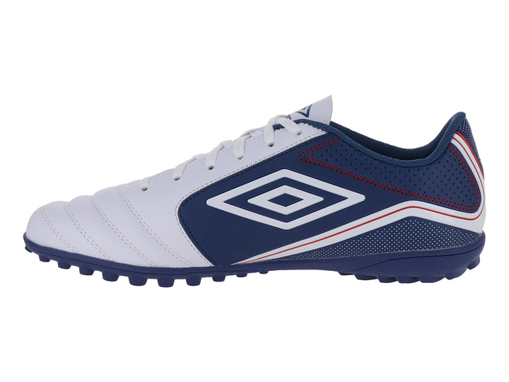Zapato de fútbol Umbro color blanco y azul con detalles rojos y suela para césped sintético.