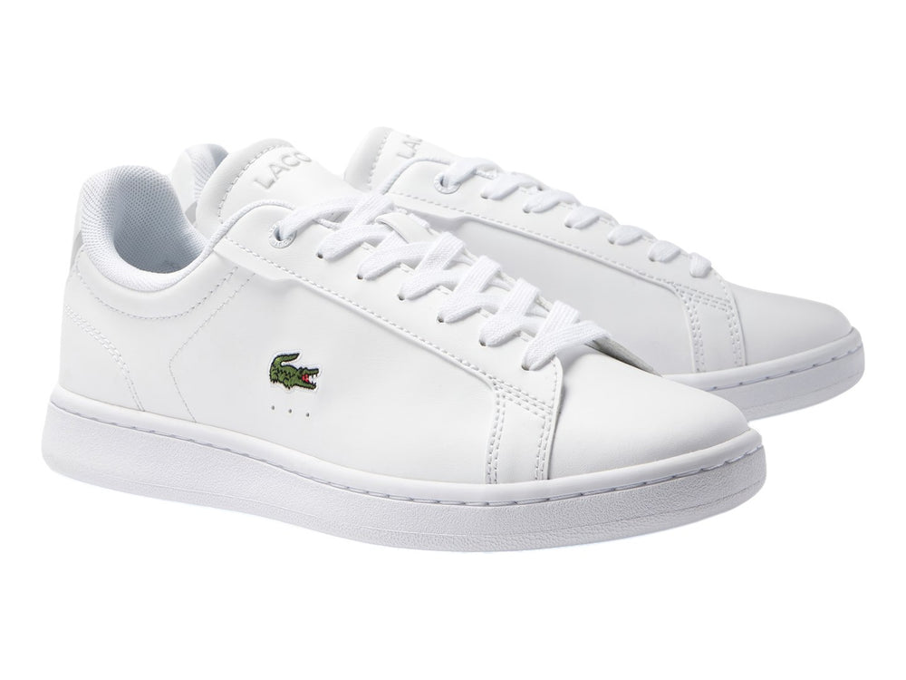 Tenis blancos de cuero para Niño marca Lacoste con logotipo del cocodrilo en el lateral.