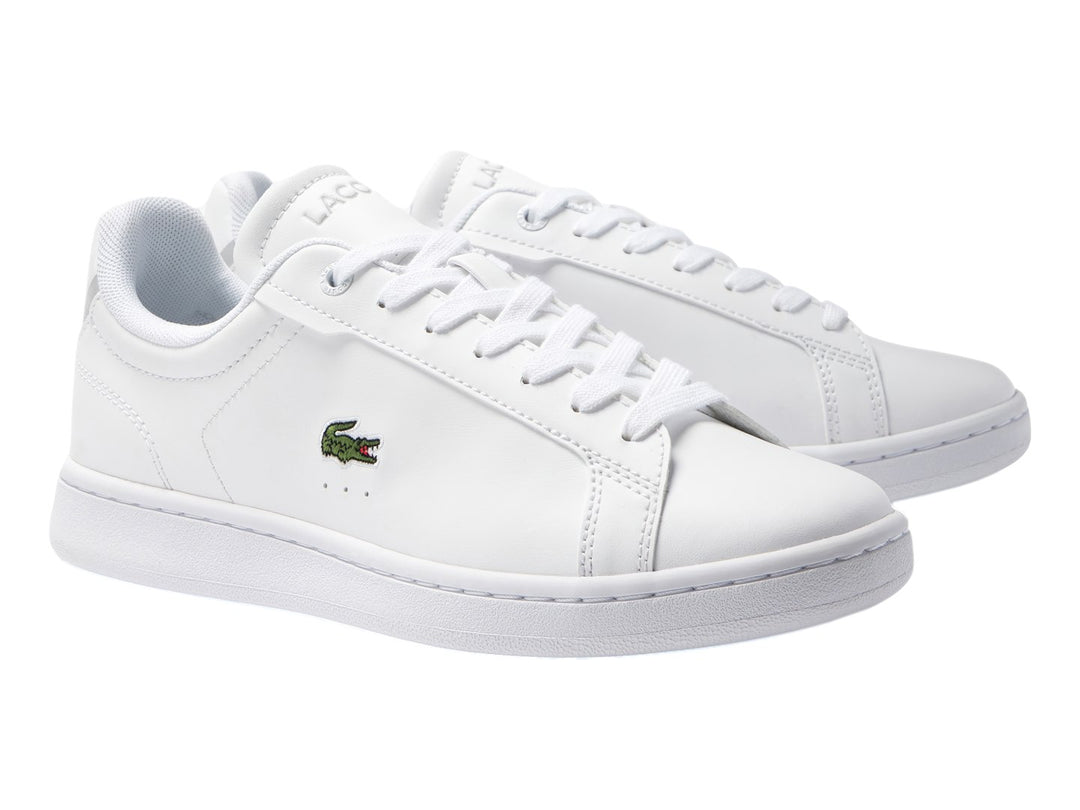 Tenis blancos de cuero para Niño marca Lacoste con logotipo del cocodrilo en el lateral.