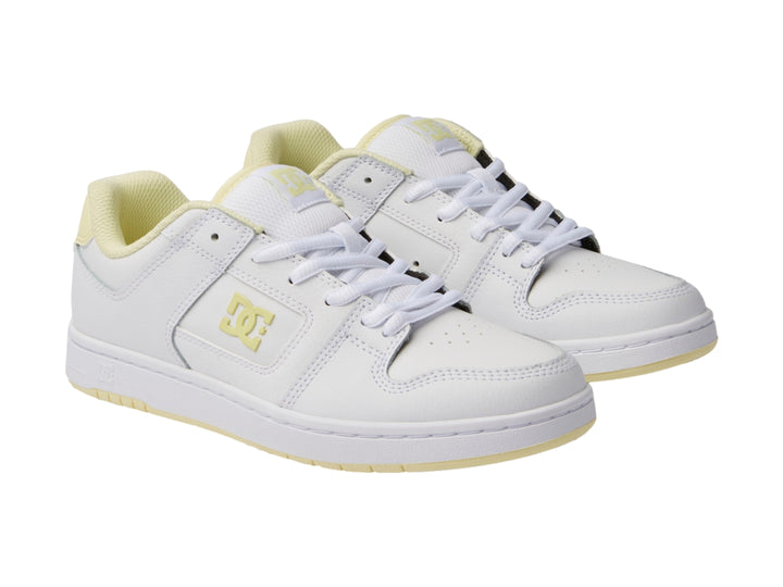 Tenis DC Shoes color blanco con detalles en amarillo y suela blanca.