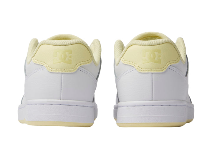 Tenis DC Shoes color blanco con detalles en amarillo y suela blanca.