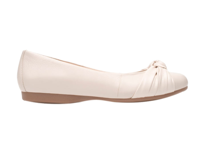 Zapato plano Flexi color latte con detalle de nudo en la punta y suela color café claro.
