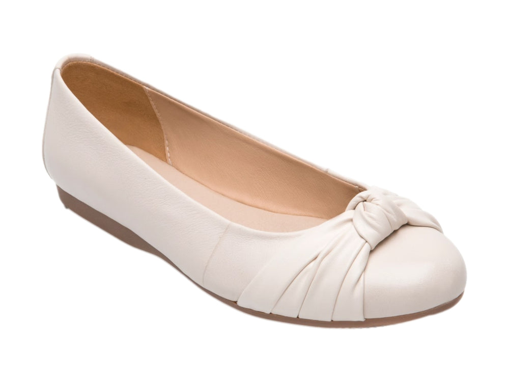 Zapato plano Flexi color latte con detalle de nudo en la punta y suela color café claro.