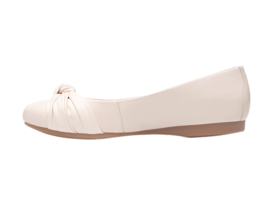 Zapato plano Flexi color latte con detalle de nudo en la punta y suela color café claro.