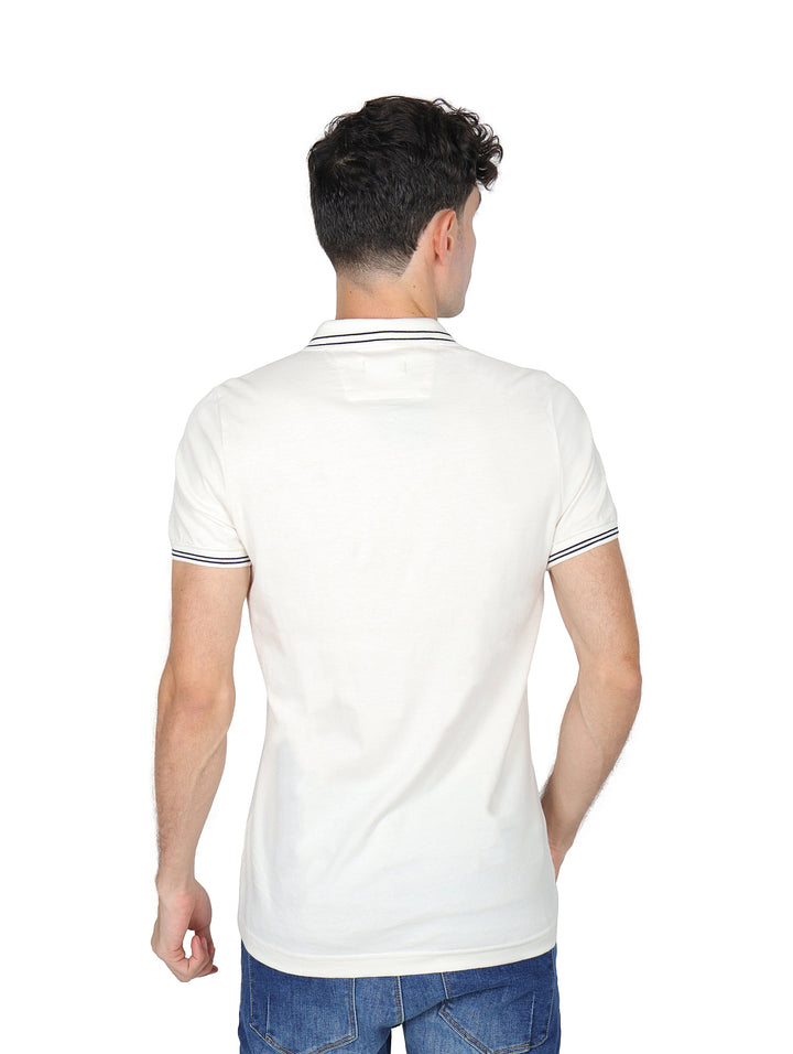 Hombre vistiendo playera polo color arena con detalles oscuros en el cuello y los bordes de las mangas.