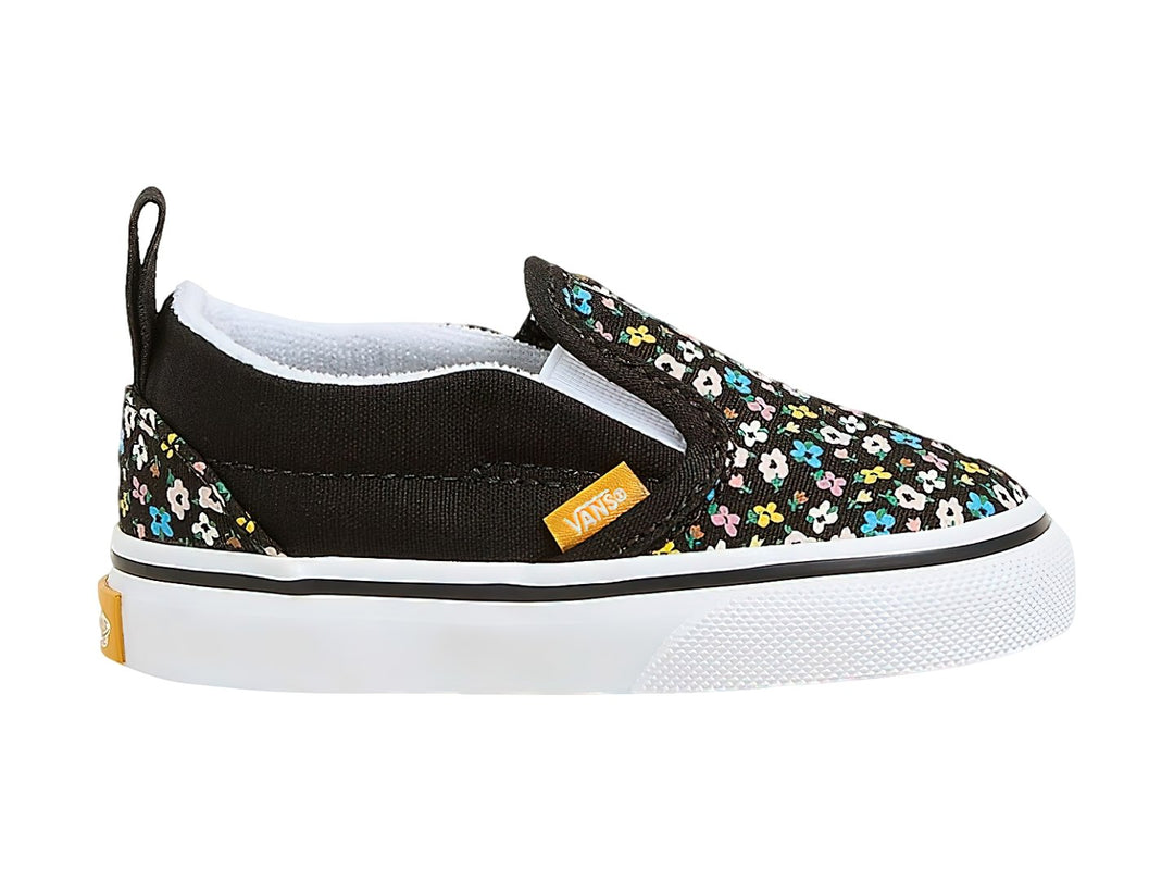 Tenis Vans slip-on negros con estampado de flores multicolores y suela blanca.