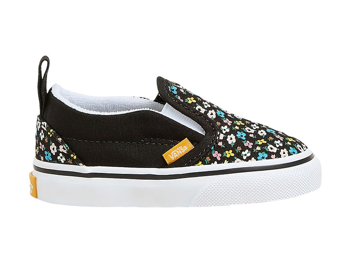 Tenis Vans slip-on negros con estampado de flores multicolores y suela blanca.