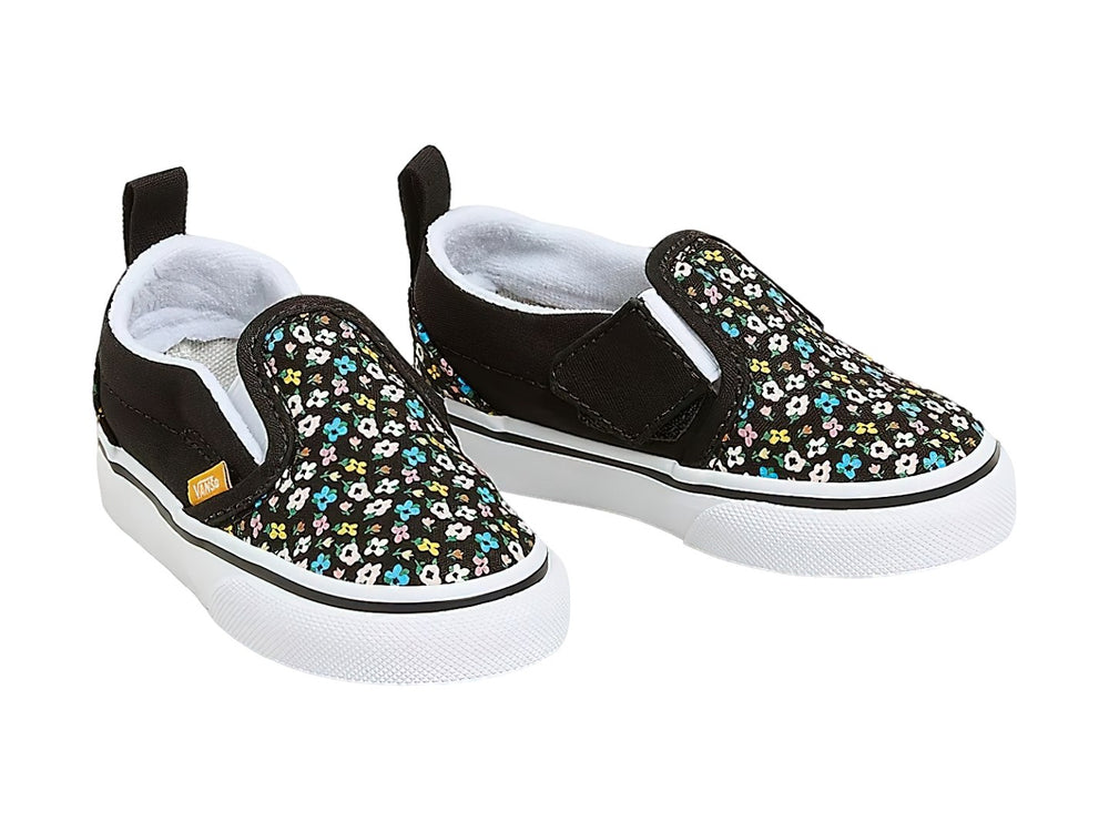 Tenis Vans slip-on negros con estampado de flores multicolores y suela blanca.