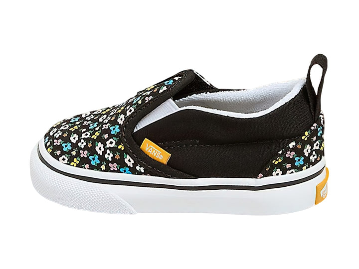 Tenis Vans slip-on negros con estampado de flores multicolores y suela blanca.