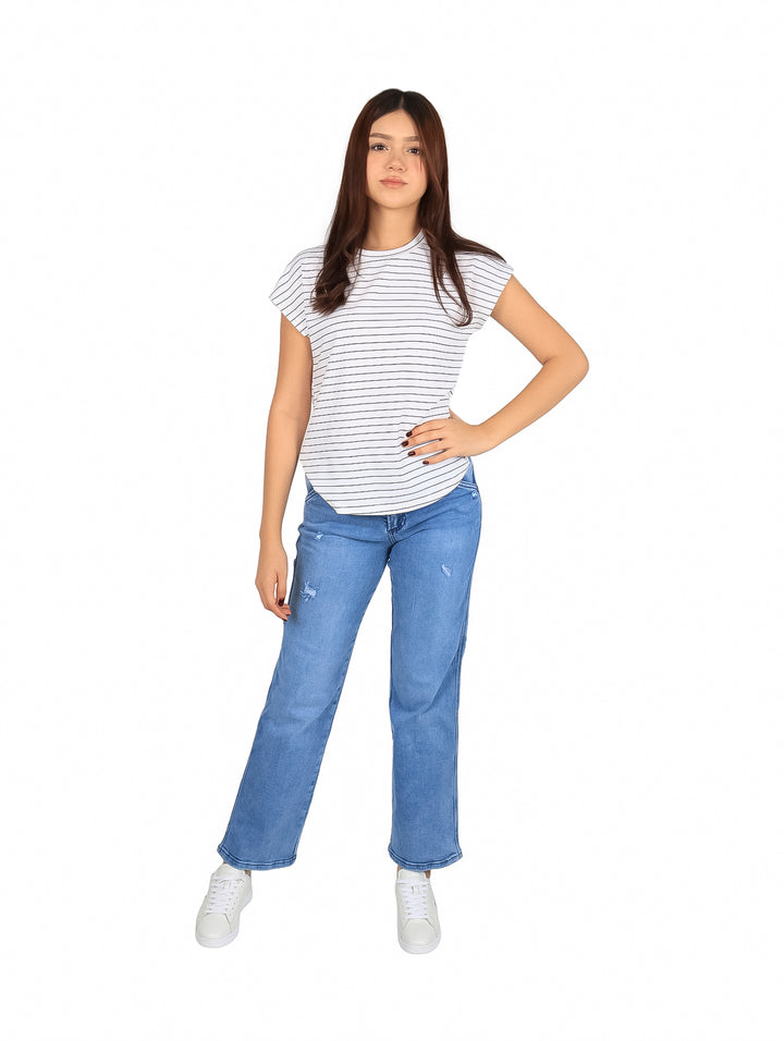 Mujer vistiendo blusa blanca con rayas negras horizontales y pantalones vaqueros azules.