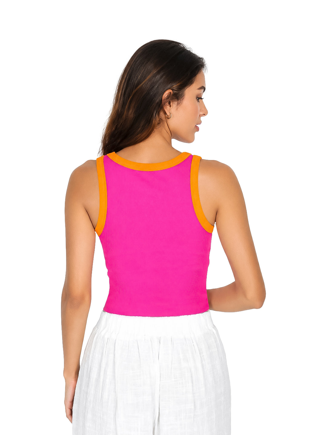 Mujer vistiendo un top ajustado color fucsia con bordes naranjas y pantalones blancos.
