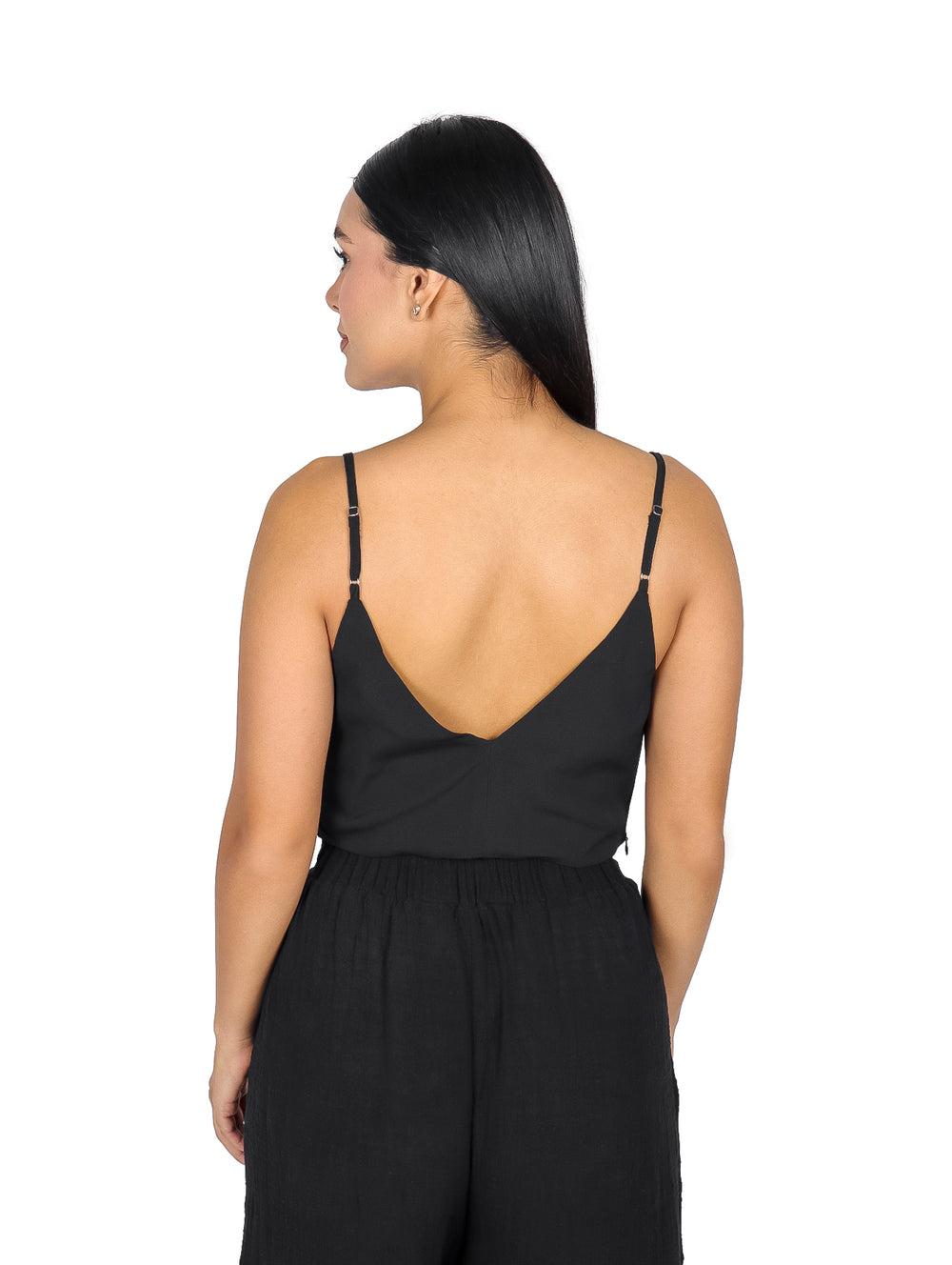 Mujer vistiendo un top negro de cuello columpio y tirantes delgados.